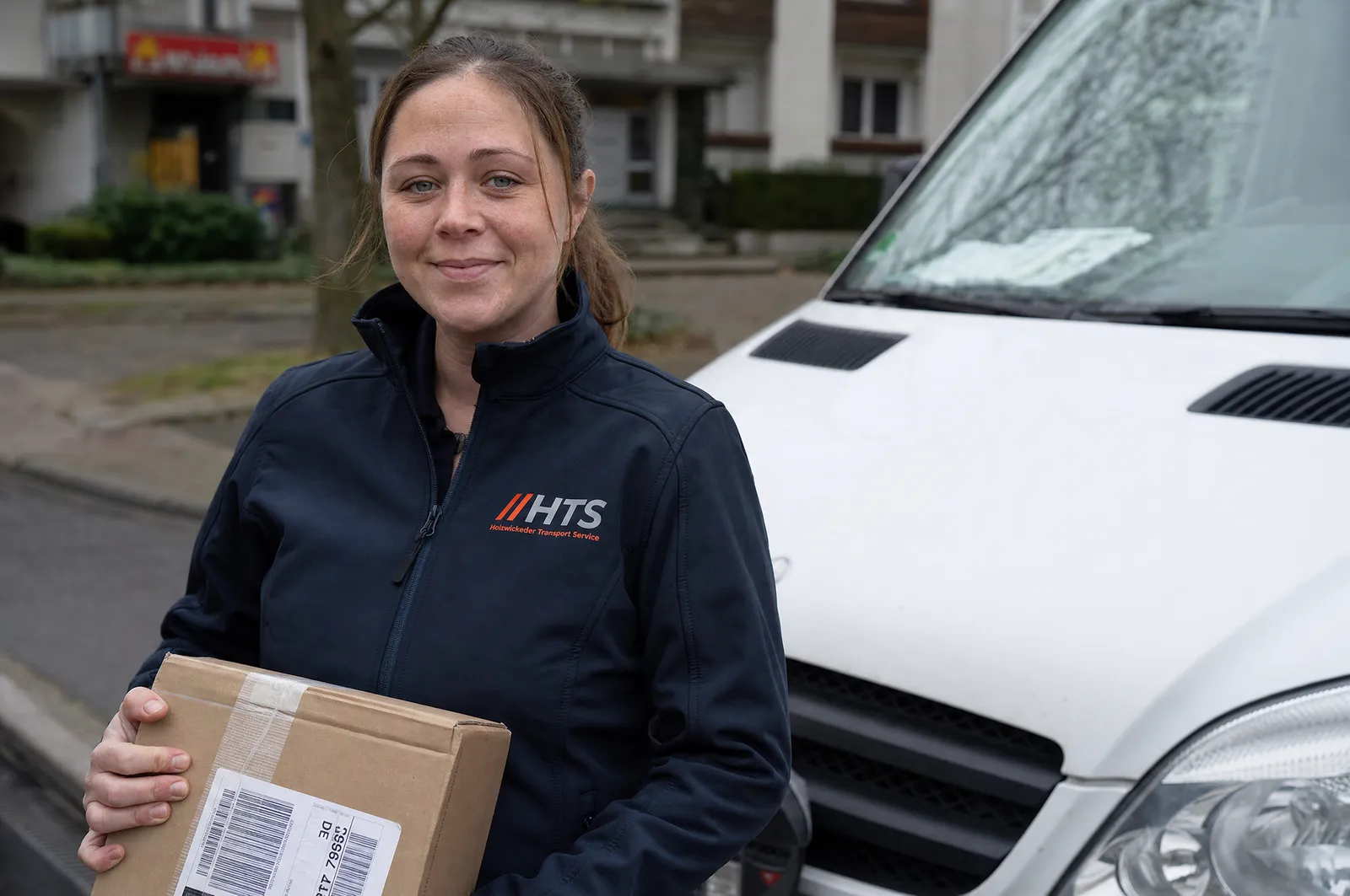 Kurierfahrerin mit Paket am Sprinter (Symbolbild)